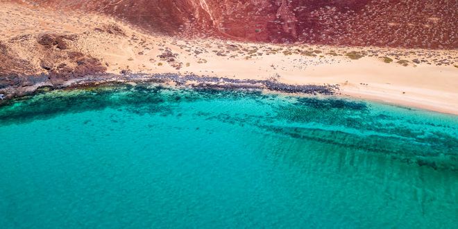 Blue waters, sandy beach and volcanic landscape in La Graciosa, Spain