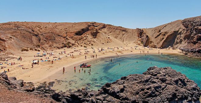 Vacanciers profitant de la plage de Papagayo, avec son sable doré et ses eaux turquoise, à Lanzarote