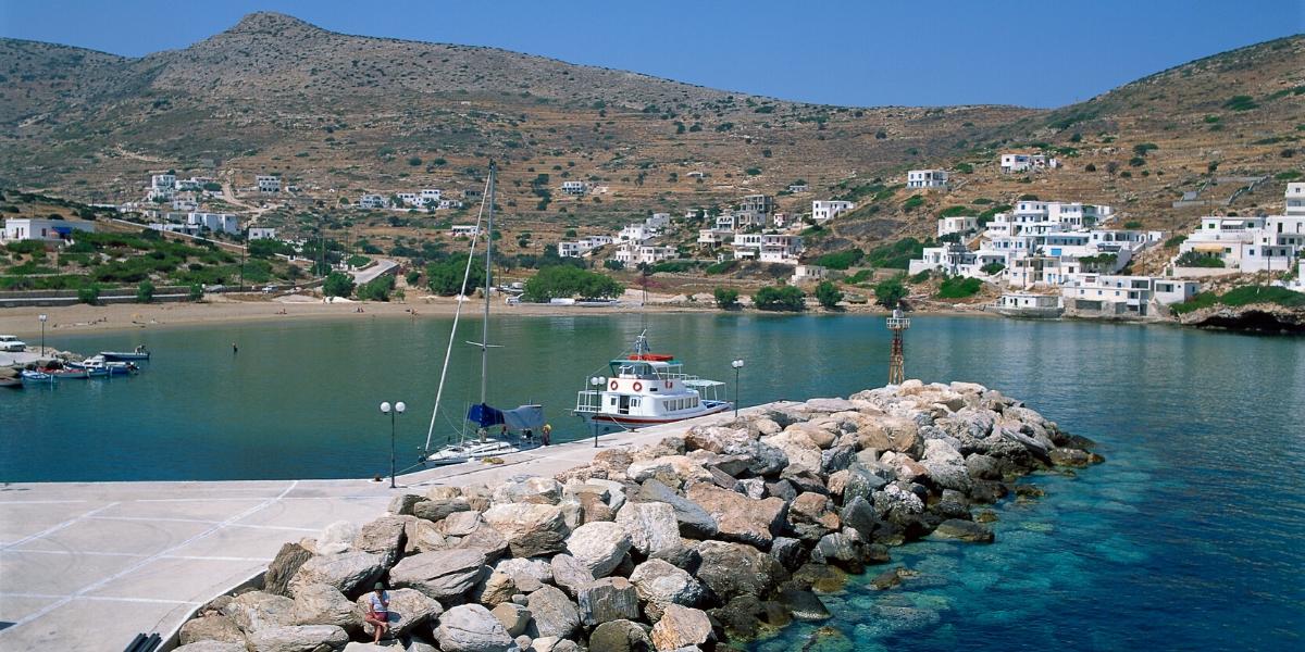 λιμάνι, κυματοθράυστης με πέτρες, άσπρα κτήρια, βάρκες, καθαρά νερά