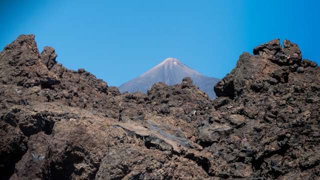 Pico del Teide asoma entre rocas volcánicas en Tenerife