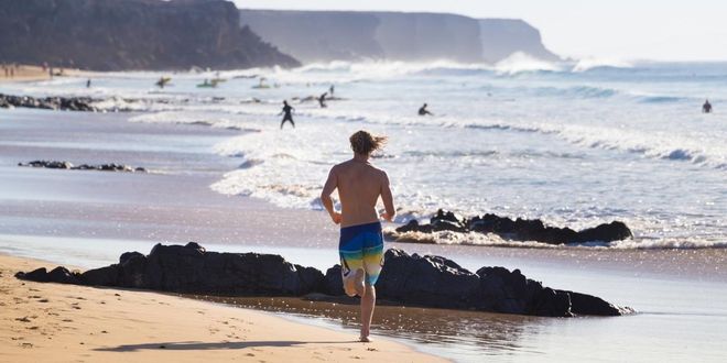Person running down a beach in the Canaries