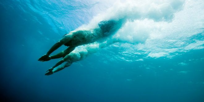 Two people diving into the water