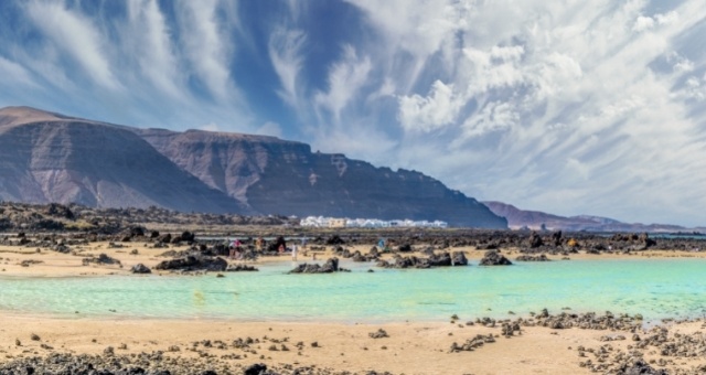 Bright sand and volcanic rocks at the beach of Caletón Blanco in Lanzarote, Spain