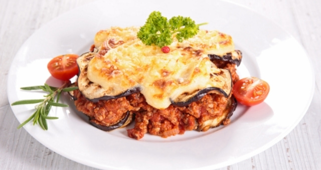 A generous slice of vegan moussaka served with cherry tomatoes 