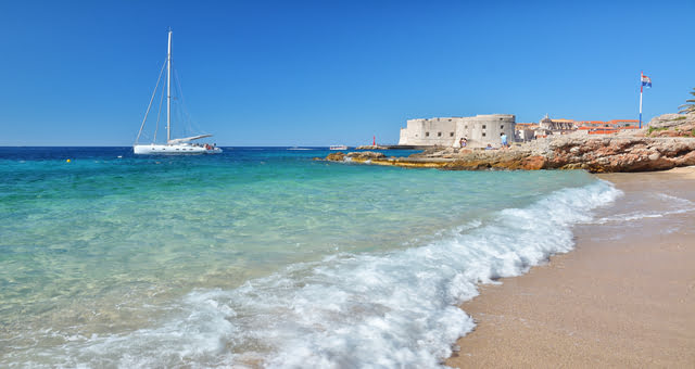 Barca a vela che naviga vicino la spiaggia di Banje a Dubrovnik, Croazia