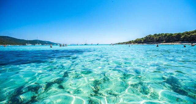 People enjoying a swim at a bay with crystal clear waters in Lastovo