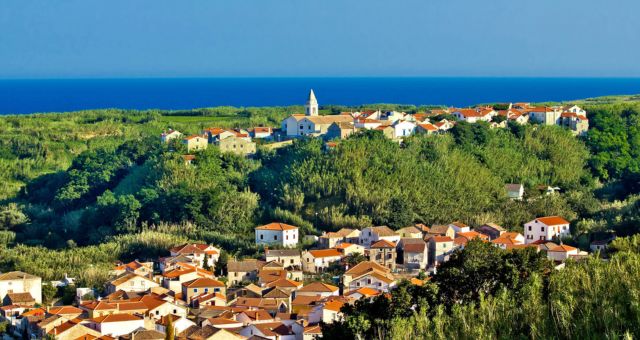 A seaside town filled with trees and stone houses on the island of Susak, Croatia