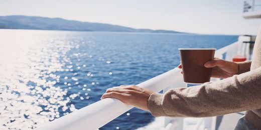 Passeggero che si gode la vista bevendo un caffè caldo sul ponte della nave per la Sardegna
