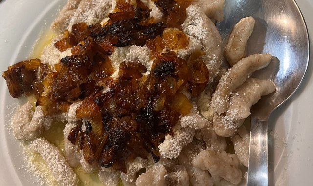 Close-up view of makarounes served with caramelized onion and grated cheese in Karpathos, Greece