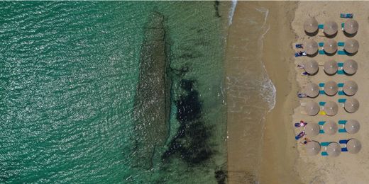 Aerial view of Plaka beach, with umbrellas and sun loungers, in Naxos island, Greece