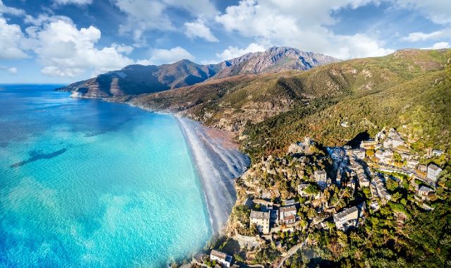 Vista panoramica della Spiaggia di Nonza, in Corsica, con montagne che sovrastano la spiaggia vulcanica