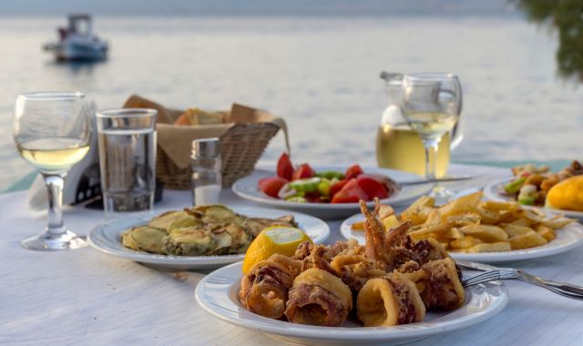 View of table by the sea with Greek seafood, appetizers and wine