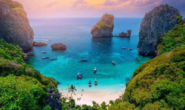 Aerial view of Nui Beach surrounded by cliffs and rock formations, in Laemtong, Koh Phi Phi Don, Thailand