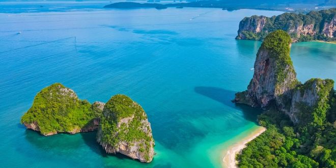 Railay Beach in Thailand seen from above, with rocks, lush tropical greenery, cliffs and white sand