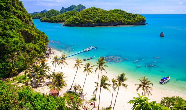 Small pier extending into the turquoise sea from a white, sandy beach in Koh Samui, Thailand