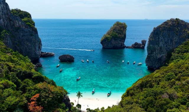Panoramic view of Nui Beach on Ko Phi Phi Don Island, in Thailand, with lush green mountains and boats in turquoise sea