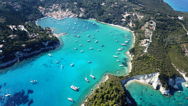 The emerald waters and coast of Paxi island filled with boats, Ionian Islands, Greece