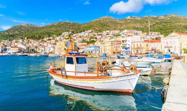 Seafront view of Vathy, in Samos, with traditional houses built on the hillside and small fishing boats floating on calm blue waters