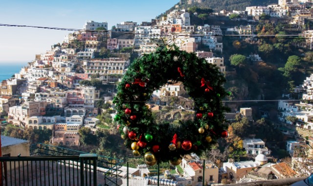 Una ghirlanda natalizia appesa su un balcone con una vista panoramica di Positano