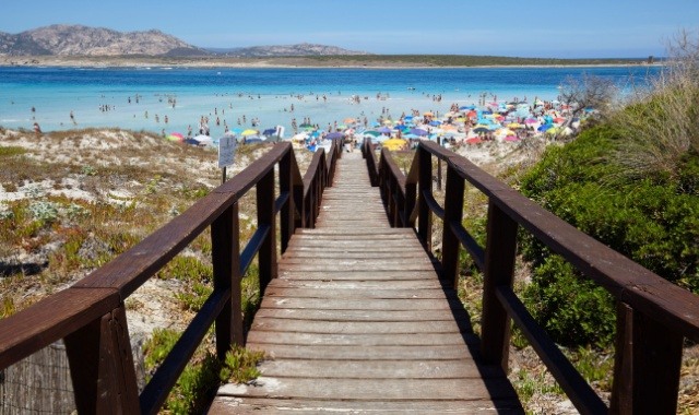 Die Holzbrücke zum Strand La Pelosa an einem belebten Tag