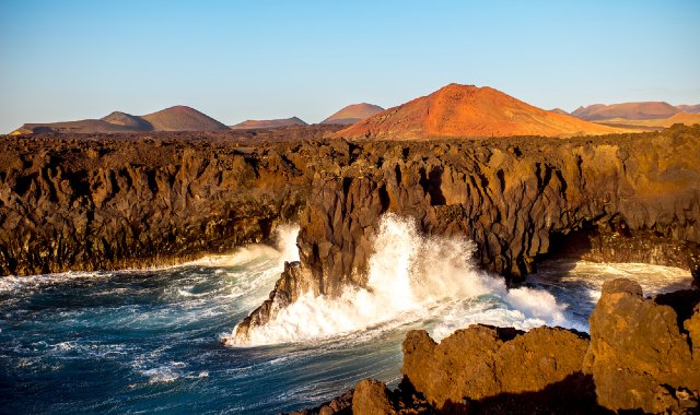 Sea waves crashing into the sea caves and rugged coastline of Los Hervideros, Lanzarote, Canaries