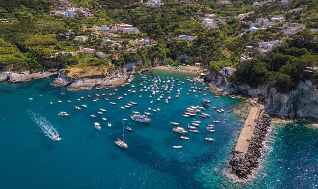 Vista panoramica di Cala Feola, circondata dal litorale roccioso e da piccole imbarcazioni