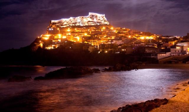 Vista di Castelsardo che si affaccia sul mare, con le luci natalizie che illuminano il borgo di notte