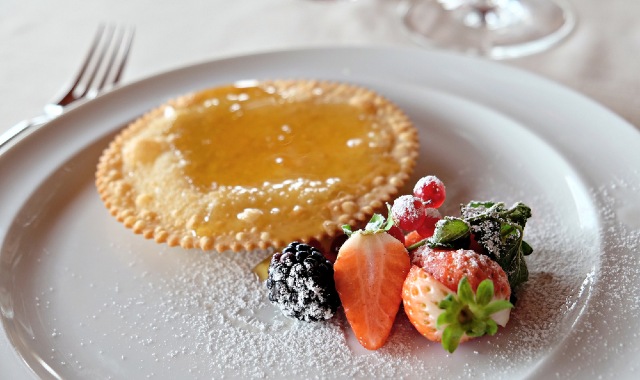 Piatto di seada, un dolce tipico sardo con ripieno di formaggio e ricoperto di miele, presentato al tavolo di un ristorante