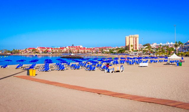 File di lettini e ombrelloni blu sulla spiaggia di Las Vistas a Tenerife