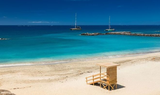 Spiaggia di Playa del Duque, a Tenerife, con una torretta di salvataggio e delle barche a vela