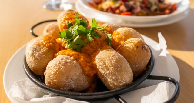 Traditional Canary Islands dish papas arrugadas served with red mojo picón sauce at an outdoor restaurant, Spain