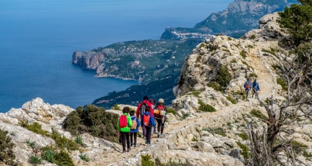 Hikers walking along the Camí de s'Arxiduc trail in the Serra de Tramuntana mountains, Mallorca, Spain