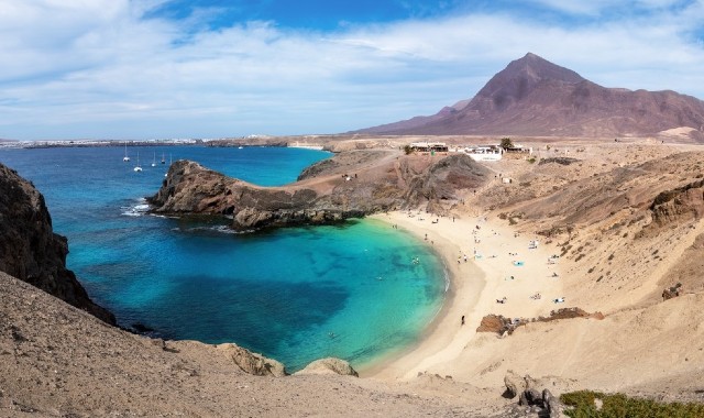 La spiaggia di Papagayo, a Lanzarote, con la sua sabbia dorata, le acque turchesi e il paesaggio vulcanico.
