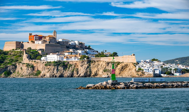 View of the walled Old Town of Ibiza, Spain, on a hill overlooking the sea, with a harbor beacon in the foreground