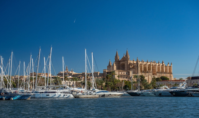A wide shot of the grand Gothic Santa Maria Cathedral of Palma overlooking a marina in Mallorca, Spain