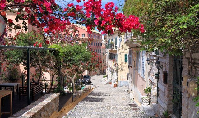 Pink bougainvillea framing a narrow stone staircase street in Corfu Old Town, Greece