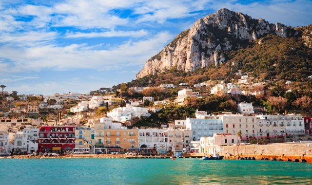 Vista di Marina Grandi, a Capri, con edifici colorati e una montagna rocciosa