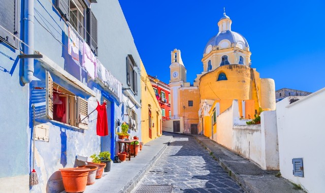 Casette colorate su una stradina acciottolata di Procida che conduce a una chiesa