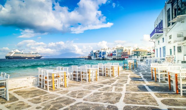 View of ferry in the distance and restaurant tables in Little Venice, Mykonos, Cyclades, Greece