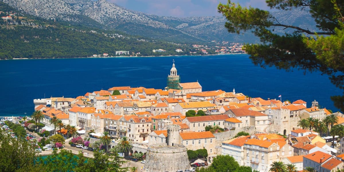 Aerial view of the historic walled town of Korčula with orange rooftops and a bell tower in Croatia