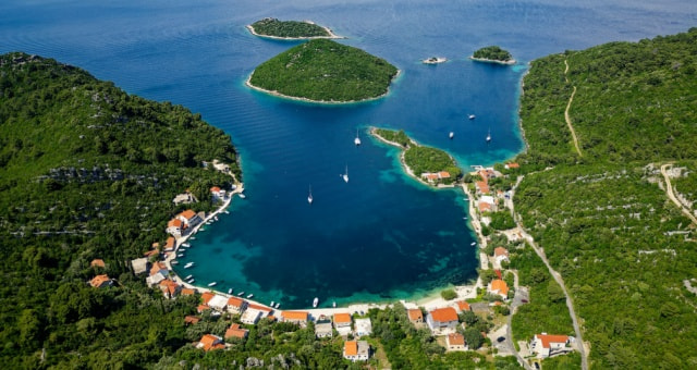 Aerial view of a deep blue bay with sailboats and small green islands in Mljet National Park, Croatia