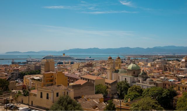 Vista panoramica degli edifici nel centro storico di Cagliari con il mare e un traghetto in lontananza