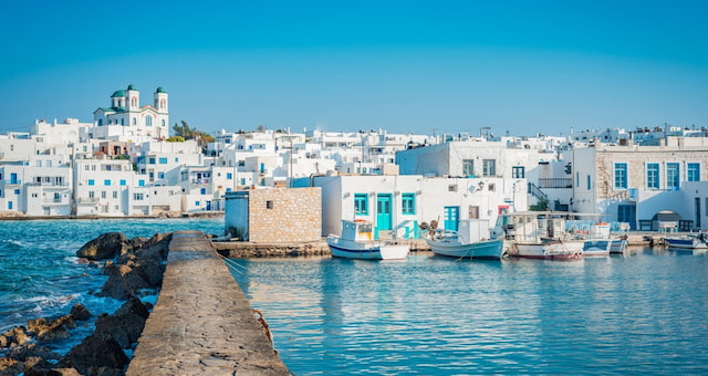 Ψαροκάικα αγκυροβολημένα σε πέτρινη προβλήτα δίπλα σε λευκά παραθαλάσσια κτίρια στην Πάρο