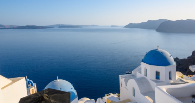 Blue-domed churches overlooking the deep blue volcanic caldera sea in Oia, Santorini, Greece