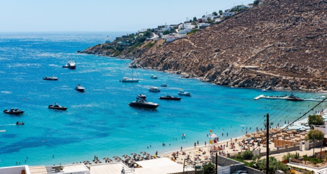 Turquoise bay filled with yachts and boats at Psarou beach in Mykonos, Greece