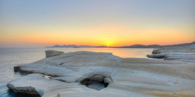 Golden sunset over the white volcanic rock formations of Sarakiniko beach in Milos, Greece