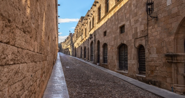 Medieval cobblestone alleyway lined with stone buildings in the Old Town of Rhodes, Greece
