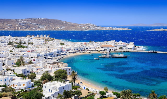 Aerial view of the whitewashed town, blue bay, and classic windmills of Mykonos island in Greece