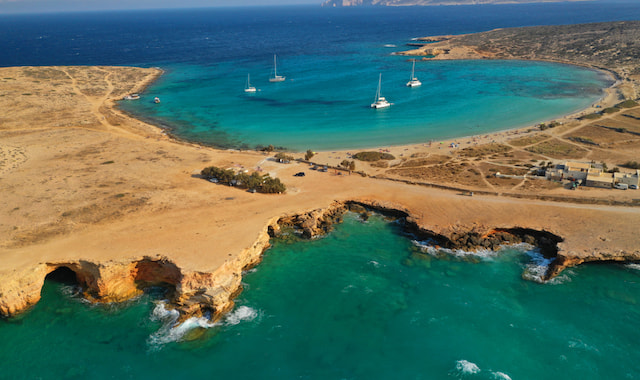 High-angle shot of sailboats anchored in the turquoise waters of the horseshoe-shaped Pori Beach in Koufonisia, Greece