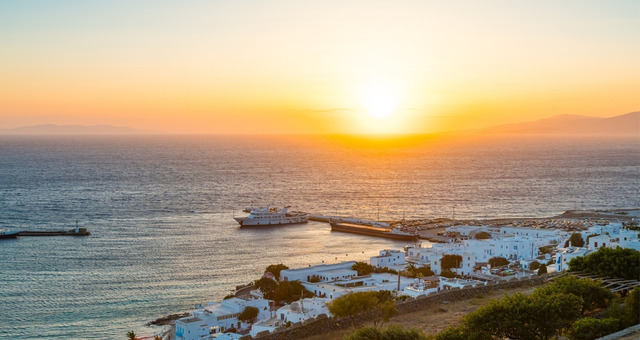 Sunset over the white buildings and harbor of Chora in Mykonos, Greece
